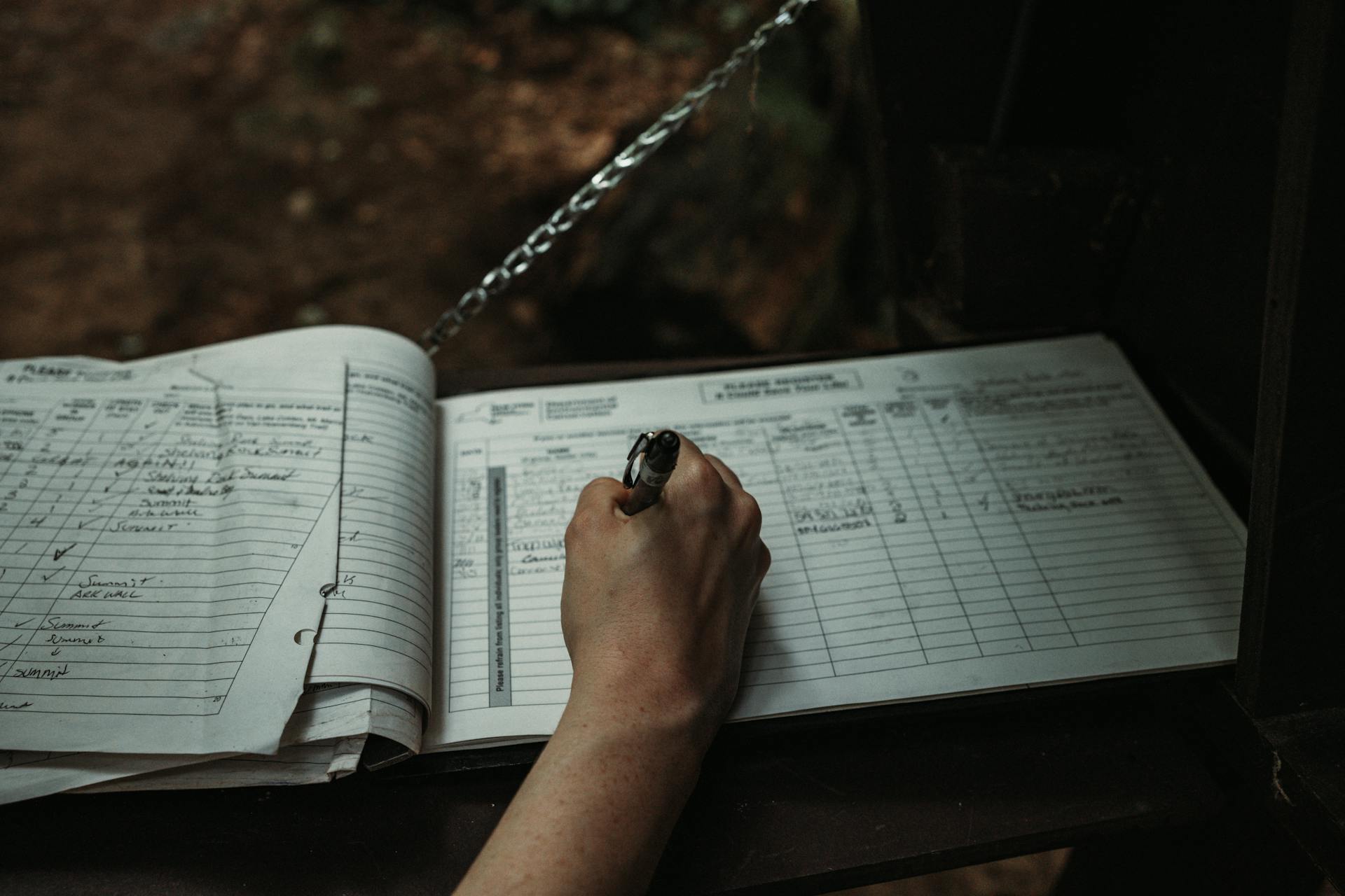 A hand filling in a paper logbook